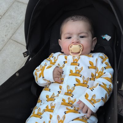 Bébé en pyjama à renards, confortablement installé dans sa poussette lors d'une promenade.